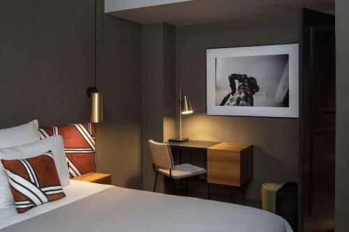 巴黎皮埃蒙特卢浮宫酒店的卧室配有一张床和一张桌子,墙上挂着一只狗