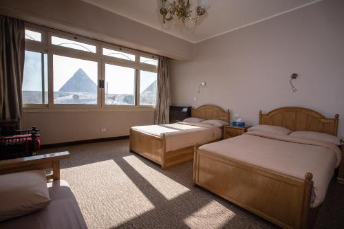 开罗卫报旅馆的一间卧室设有两张床,享有金字塔的景色