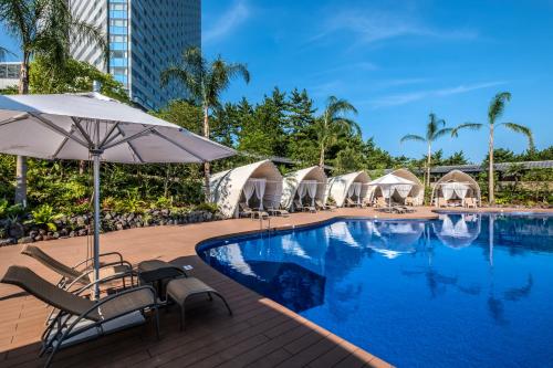 宫崎喜来登顶级海洋度假酒店的游泳池,带椅子和遮阳伞