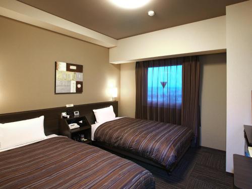 富山富山因特路线酒店的酒店客房设有两张床和窗户。