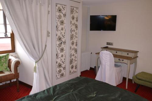 Lusignan乐查普罗格酒店的一间卧室配有一张床、一张书桌和一台电视
