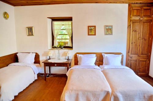 科瓦切维卡Kalinia Guesthouse B&B的配有桌子和窗户的客房内的两张床