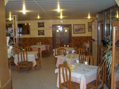 Numancia de la Sagra梅斯旅馆的一间设有白色桌子和木椅及桌子的餐厅