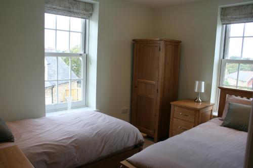 尚克林Highlands Apartment 2的一间卧室设有两张床、一个梳妆台和两个窗户。