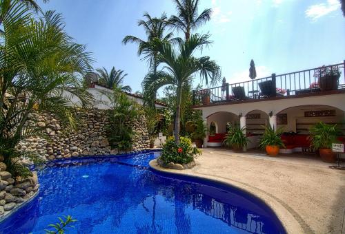 埃斯孔迪多港Villas Carrizalillo的棕榈树屋前的游泳池
