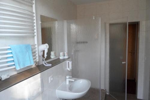 Dallgow斯波林斯霍夫酒店的白色的浴室设有水槽和淋浴。