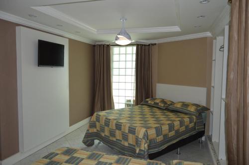 马卡埃Hospedagem Belo Horizonte的卧室配有一张床,墙上配有电视。