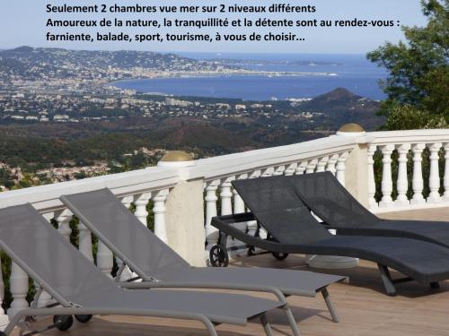 St Jean de l’Esterel爱斯特尔全海景住宿加早餐旅馆的阳台上摆放着几把椅子