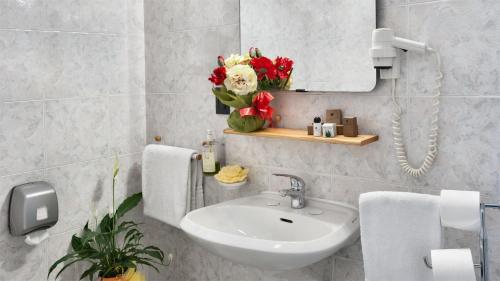 米兰伽玛酒店的浴室设有水槽、镜子和鲜花