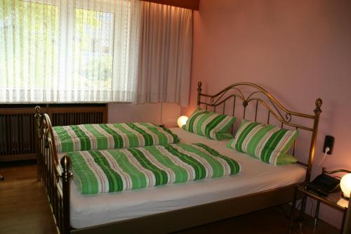 汉堡Albertus Paris Aparthotel的一张带绿色和白色枕头的床和窗户