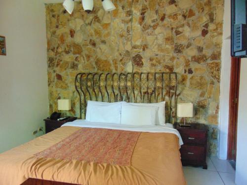 马那瓜Managua Hills的一间卧室设有一张床和石墙