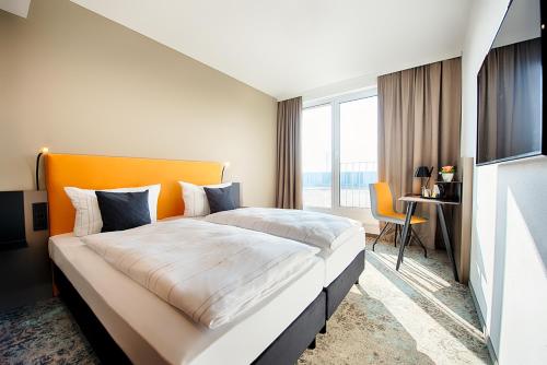 莱比锡LOGINN Hotel Leipzig的酒店客房设有一张大床和一张书桌。