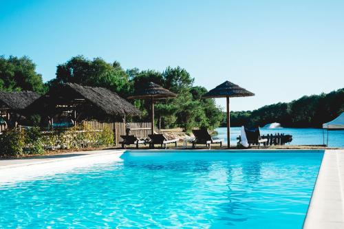 拉卡诺Villa Domaine de Pitrot的水边带椅子和遮阳伞的游泳池