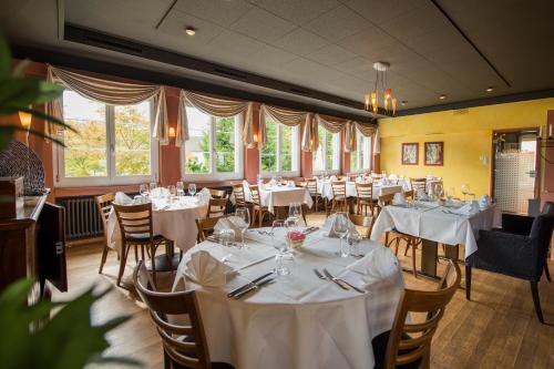 Hertenstein诺伊豪斯餐厅酒店的一间设有白色桌椅和窗户的用餐室