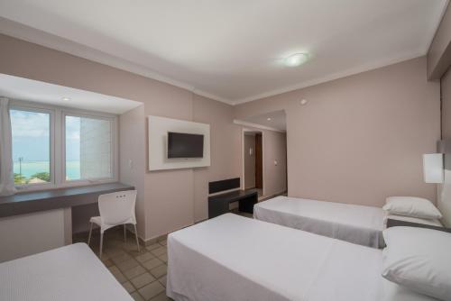 马塞约Hotel Sete Coqueiros的一间卧室配有两张床、一张桌子和一台电视。