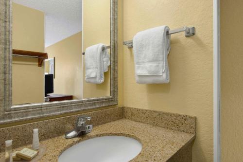 盖恩斯维尔Baymont By Wyndham Gainesville I-75的浴室配有盥洗盆、镜子和毛巾