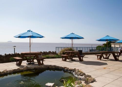 滨海韦斯顿安可尔海德酒店的一组野餐桌,配有雨伞和池塘