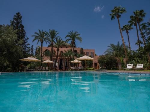 马拉喀什达艾尼文花园酒店&鸟类动物园 的一座棕榈树大型游泳池和一座建筑