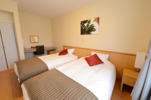 伊东内萨城崎旅馆的酒店客房配有两张床和一张书桌