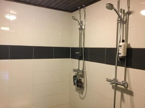 Rautuskylä玛扎塔罗朱尔塔宾馆的浴室铺有黑白瓷砖,设有淋浴。