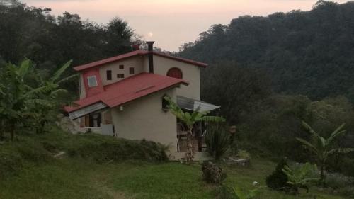 XicoCasa de campo vacacional "Tres Soles" en Xico, Veracruz的山丘上一座带红色屋顶的小房子