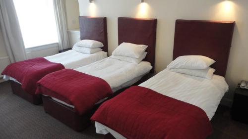 格拉斯哥Sandyford Hotel的酒店客房,配有三张带红色毯子的床