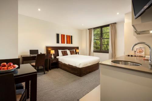 堪培拉堪培拉西部酒店的酒店客房配有一张床、一张书桌和一间厨房。