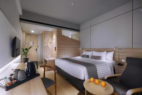 芝卡朗Harper Cikarang by ASTON的酒店客房配有床、沙发和桌子。