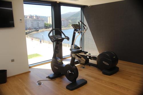 比韦罗Hotel U Viveiro的健身房设有两台跑步机和大窗户