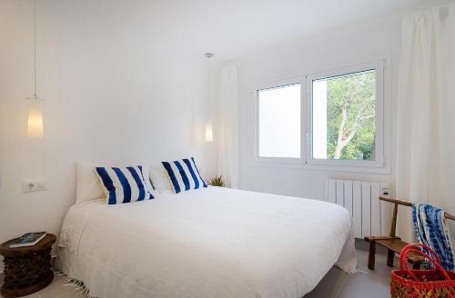 卡莱利亚德帕拉弗鲁赫尔Azteka Blue 2 Bed Apartment Calella de Palafrugell的白色卧室配有一张带蓝色和白色枕头的大床