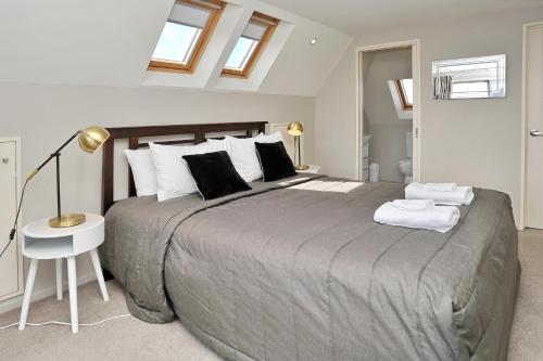 基督城Regents 94B - Christchurch Holiday Homes的一间卧室配有一张大床、一盏灯和一张桌子