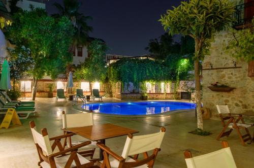 安塔利亚White Garden Hotel-Adult Only的天井配有桌子,晚上设有游泳池