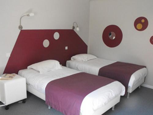 阿瓦隆Logis Hôtel Restaurant Les Capucins的酒店客房设有两张床和红色及白色的墙壁。