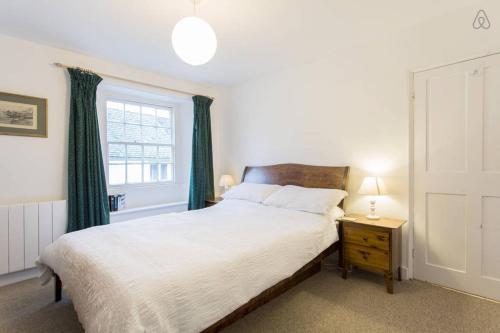圣莫斯Fisherman's Cottage的一间卧室配有一张带绿色窗帘的床和窗户。