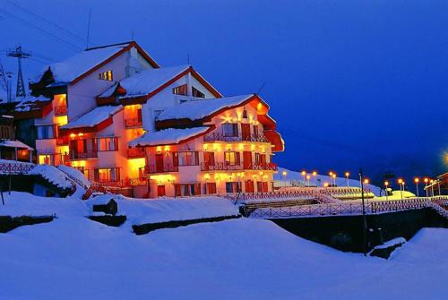 乔斯希马特Ski & Snow Cliff Top Club Holiday Resort at Auli, Uttarakhand的一座大房子,晚上有雪