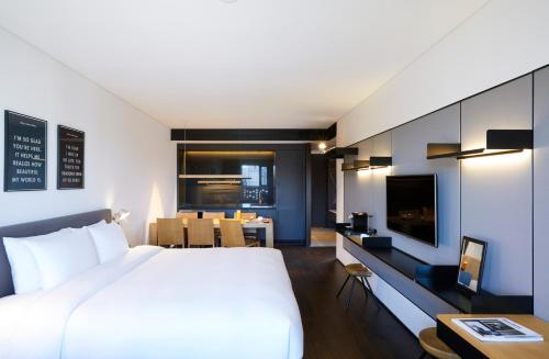 首尔GLAD Yeouido的一间卧室配有一张大床和一张带电视的书桌。