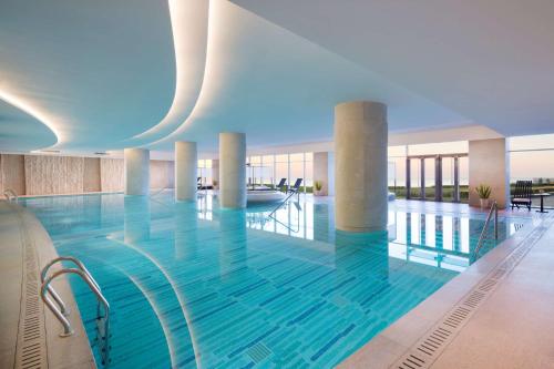 青岛青岛山港凯悦酒店 （石老人海水浴场·会展中心）的大楼内的一个蓝色海水游泳池
