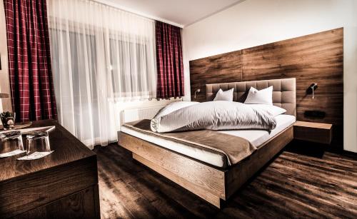 齐勒河谷采尔塔克希霍夫活跃酒店的一间卧室配有一张大床和木制床头板