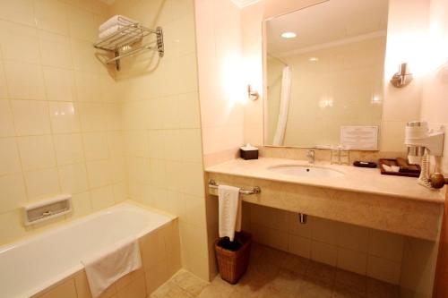 名古屋哈默尼套房酒店的一间带水槽、浴缸和镜子的浴室