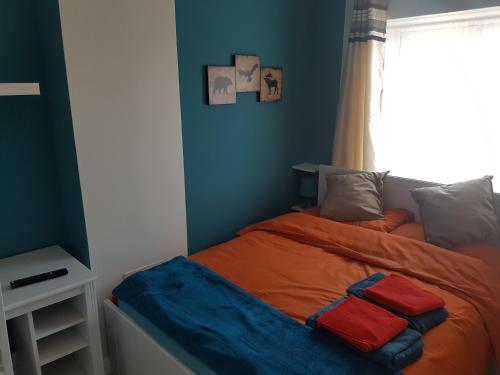 塞特福德St Giles, Thetford, 2BR House的一间卧室配有一张蓝色墙壁的床和一扇窗户