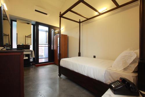 吉隆坡天井酒店的一间卧室配有一张床和一张书桌及电话
