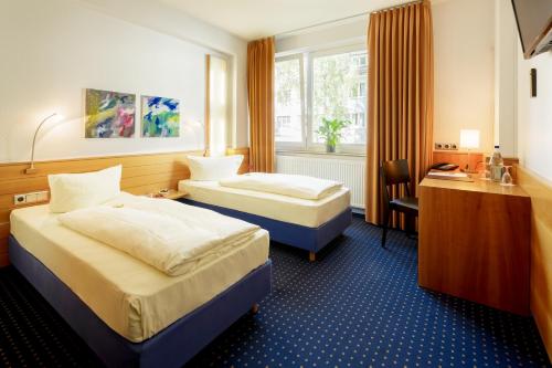 科隆MesseHotel Köln-Deutz的酒店客房配有两张床和一张书桌