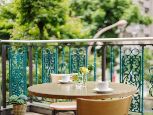 冈山冈山后乐酒店的阳台上的桌子上放着两杯,花瓶里放着鲜花