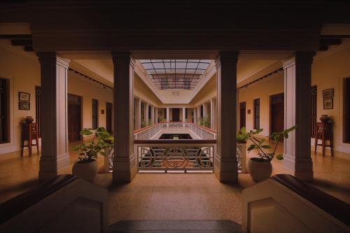 ChettinaduVisalam Chettinad Palace - CGH Earth的建筑里大走廊上,有盆栽植物