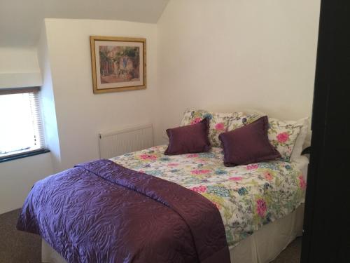 布拉克利Cottage on the Green的一间卧室配有一张带紫色床单和紫色枕头的床