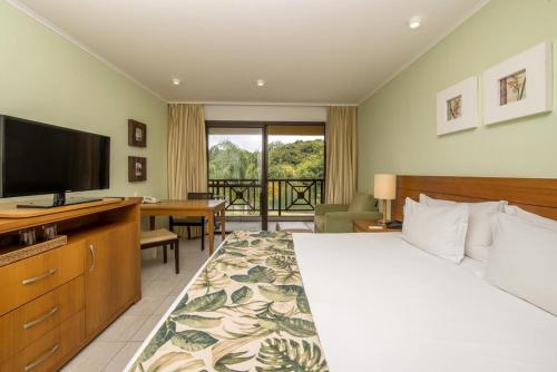 安格拉杜斯雷斯Flat particular no Resort em Angra Dos Reis的配有一张床和一台平面电视的酒店客房
