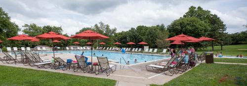 兰开斯特Circle M Camping Resort 24 ft. Yurt 2的一个带椅子和红色遮阳伞的游泳池