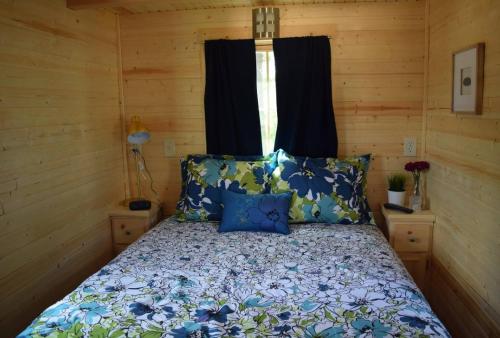 南安普敦Tuxbury Pond Camping Resort Tiny House Clara的一间卧室配有一张带蓝色枕头的床和一扇窗户。