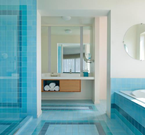 洛杉矶Beverly Laurel Hotel的浴室铺有蓝色瓷砖,配有水槽和镜子