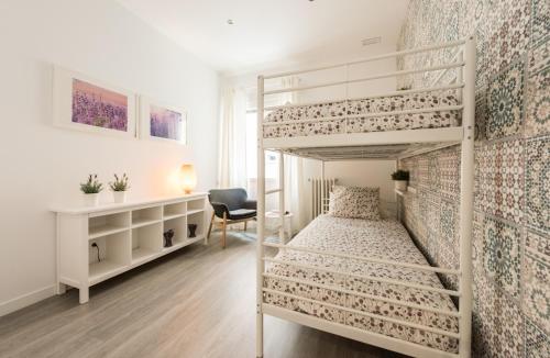 马德里古兹曼生活公寓的一间卧室配有两张双层床和一张书桌